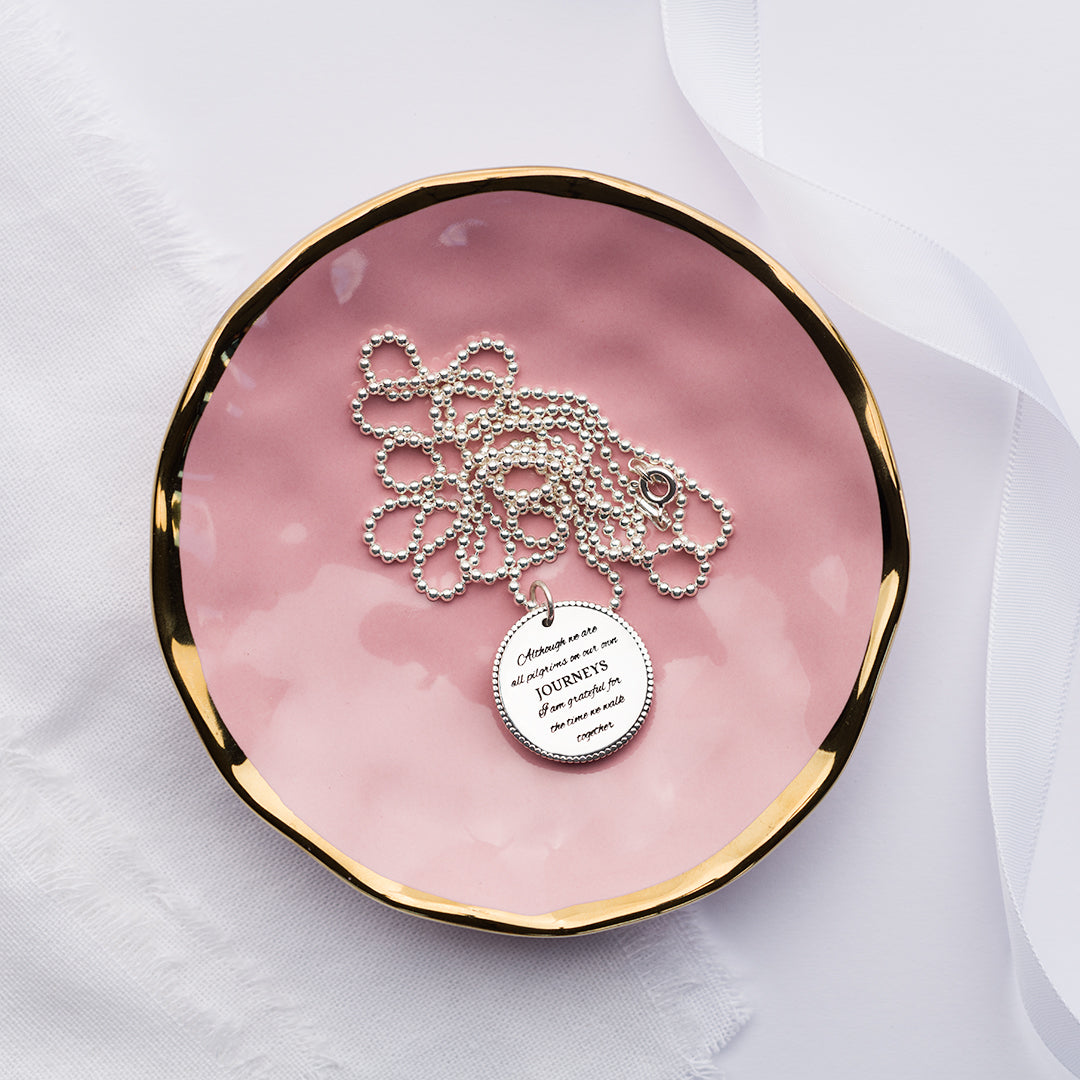 Although we are all pilgrims on our own journeys charm on a pink plate