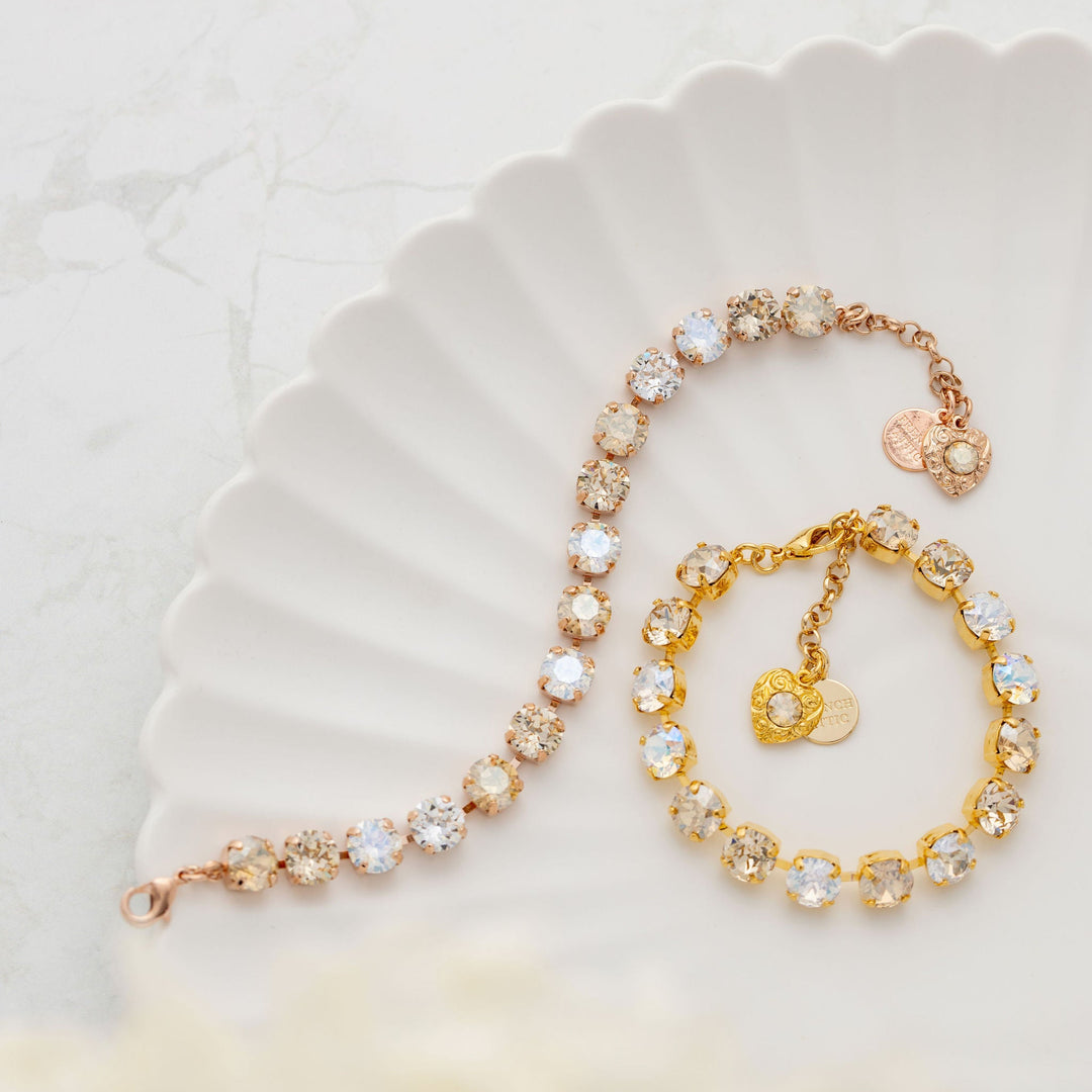 Gold and crystal bracelet on a white scalloped plate with a soft focus background