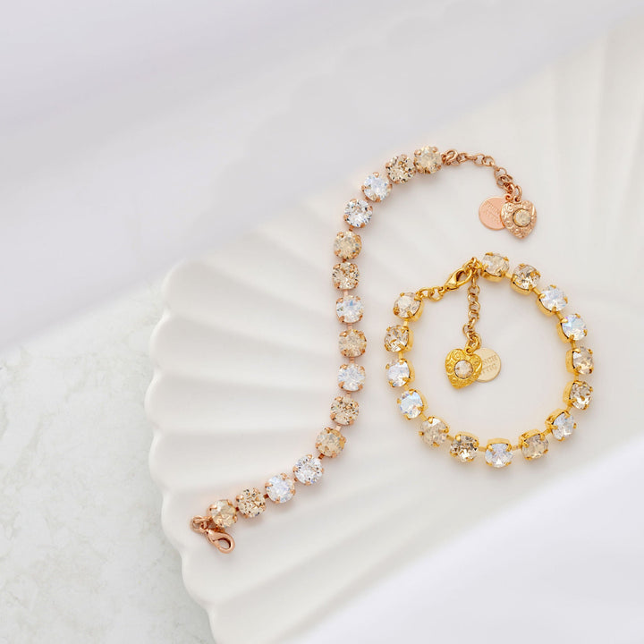 Two crystal tennis bracelets on a white shell with a white background