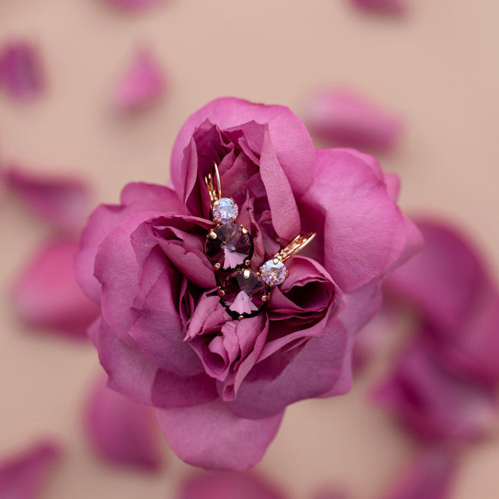 Pink crystal earrings on a pink rose with blurred pink petals in the background